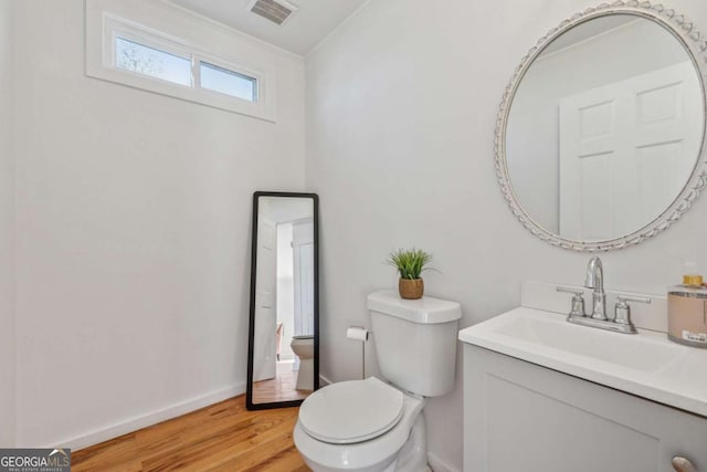 bathroom with visible vents, toilet, ornamental molding, wood finished floors, and baseboards