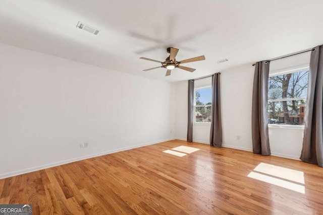 unfurnished room with a ceiling fan, visible vents, light wood-style flooring, and baseboards