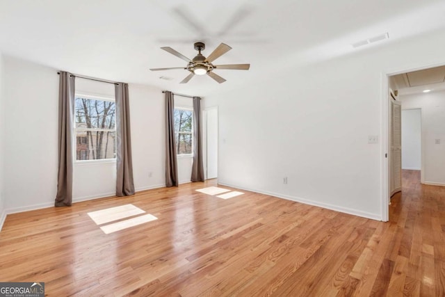 unfurnished room featuring attic access, visible vents, baseboards, light wood-style flooring, and ceiling fan