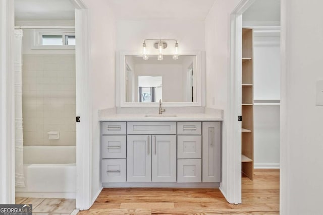 bathroom with shower / tub combo, vanity, and wood finished floors