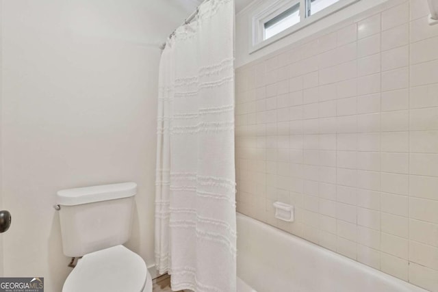 bathroom featuring shower / tub combo and toilet