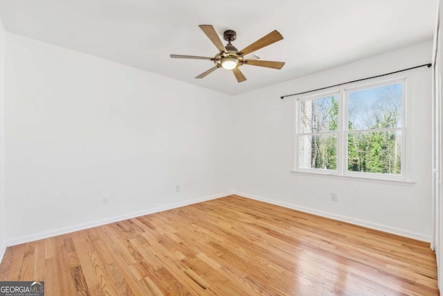 empty room with light wood finished floors, baseboards, and a ceiling fan