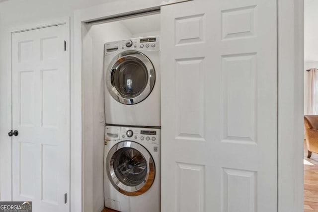 clothes washing area with laundry area, wood finished floors, and stacked washer / drying machine