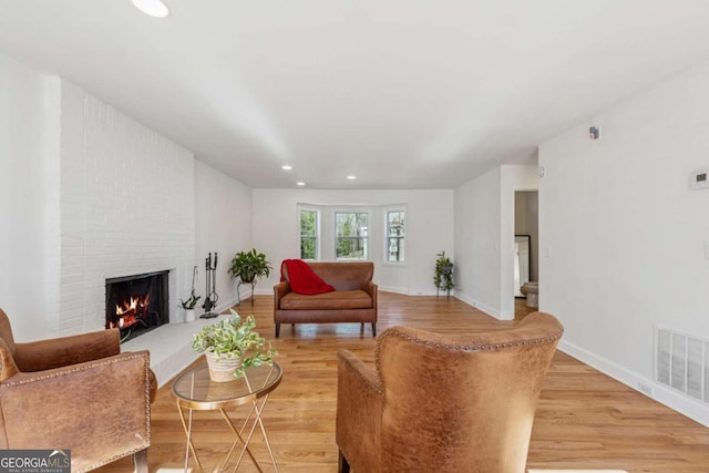 living room with recessed lighting, visible vents, light wood-style flooring, a brick fireplace, and baseboards