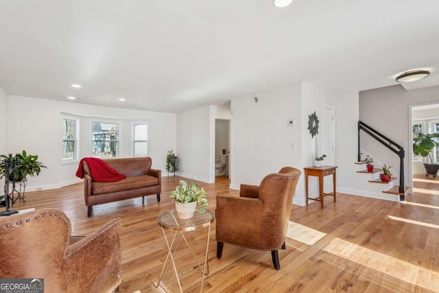 living area with light wood-style floors, recessed lighting, stairway, and baseboards