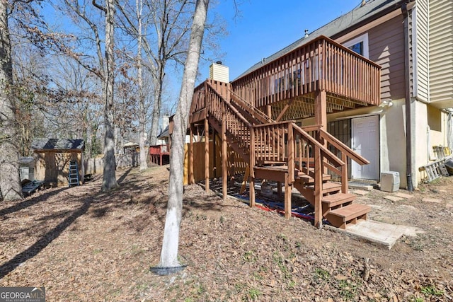 back of house with a storage unit, an outbuilding, a wooden deck, and stairs