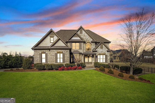 view of front of home with french doors, brick siding, a lawn, and fence