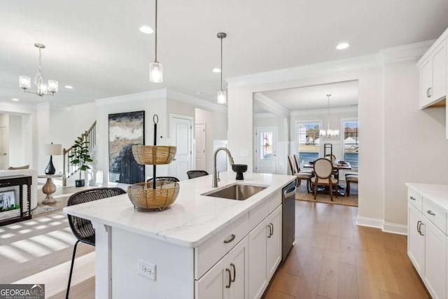 kitchen with stainless steel dishwasher, a notable chandelier, a sink, and wood finished floors