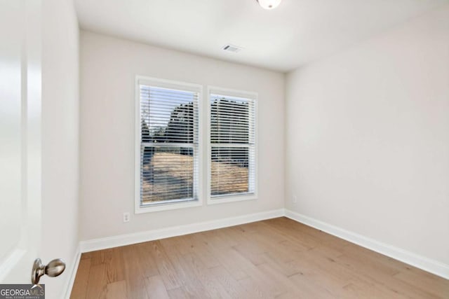 unfurnished room featuring a healthy amount of sunlight, baseboards, and wood finished floors