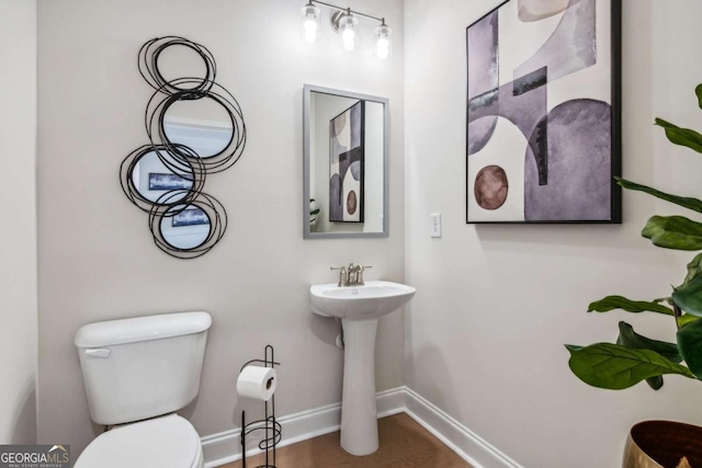 bathroom with a sink, wood finished floors, toilet, and baseboards