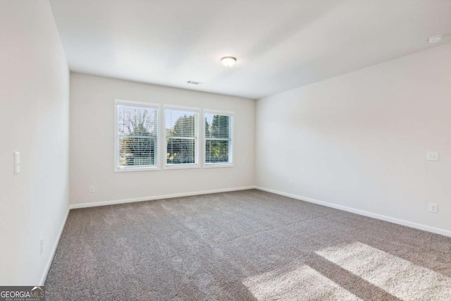 carpeted spare room with visible vents and baseboards