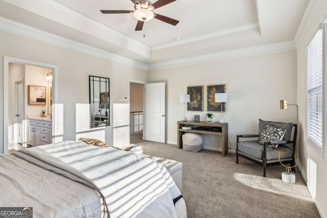 carpeted bedroom with ornamental molding, a raised ceiling, connected bathroom, and baseboards