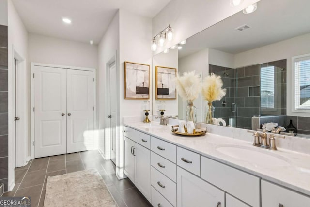 full bath with double vanity, a shower stall, visible vents, and a sink