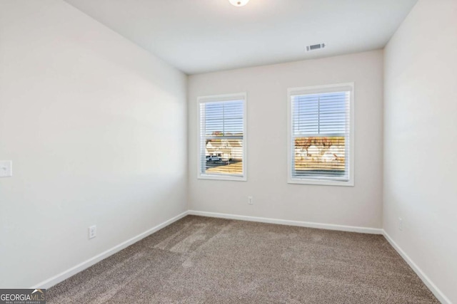 carpeted spare room featuring visible vents and baseboards