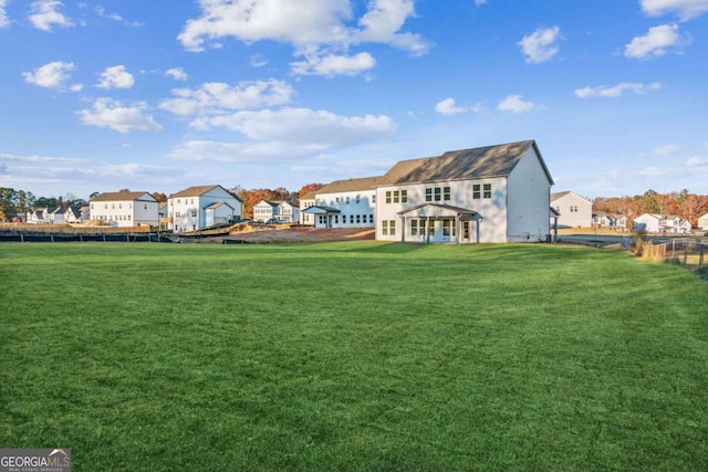 back of property featuring a lawn, fence, and a residential view