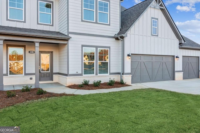 view of front of home featuring board and batten siding, a front yard, a shingled roof, and driveway