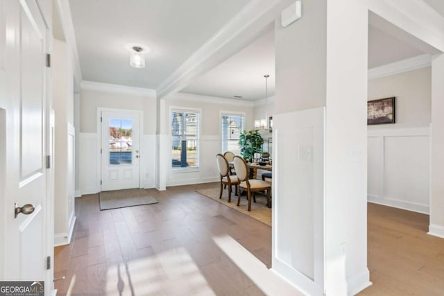 foyer with ornamental molding, wood finished floors, and a decorative wall