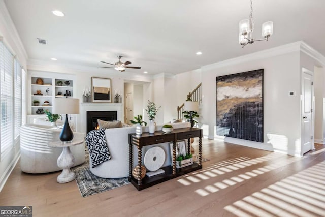 living room featuring recessed lighting, wood finished floors, visible vents, a glass covered fireplace, and crown molding