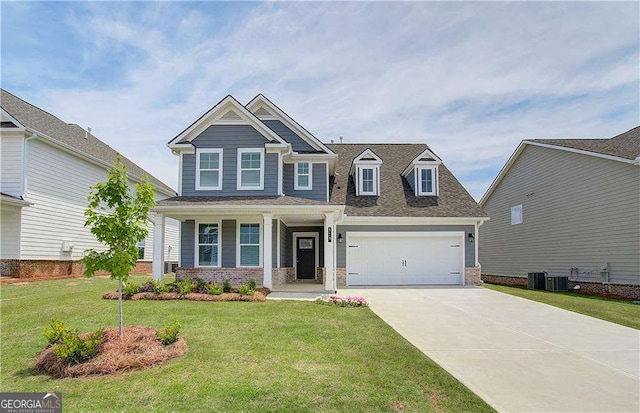 craftsman-style house featuring cooling unit, a garage, brick siding, driveway, and a front lawn