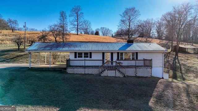 view of front of house featuring a front lawn, metal roof, a chimney, and a wooden deck