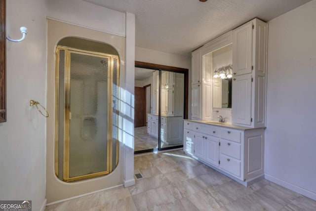 bathroom featuring a stall shower, vanity, and baseboards