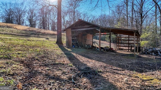 view of outbuilding with a carport, an outdoor structure, and driveway