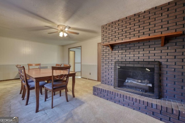 carpeted dining area featuring a fireplace, a ceiling fan, and a textured ceiling