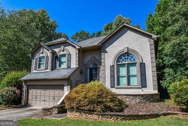 view of front facade with driveway, a shingled roof, a garage, and stucco siding