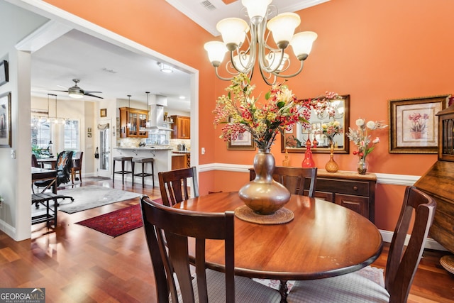 dining space featuring ceiling fan with notable chandelier, wood finished floors, visible vents, and baseboards