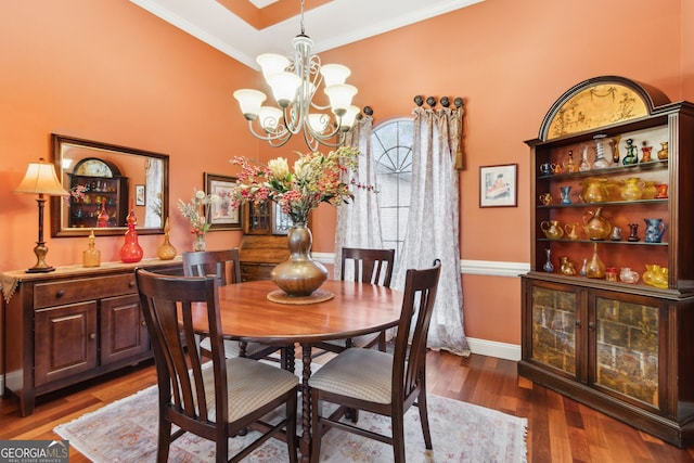 dining area with crown molding, a notable chandelier, baseboards, and wood finished floors