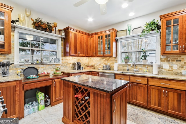 kitchen featuring a kitchen island, a sink, decorative backsplash, and light stone countertops