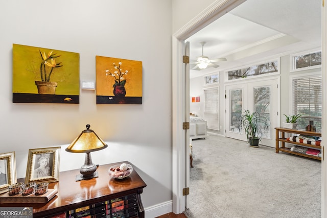 hallway with baseboards, a raised ceiling, french doors, crown molding, and carpet flooring