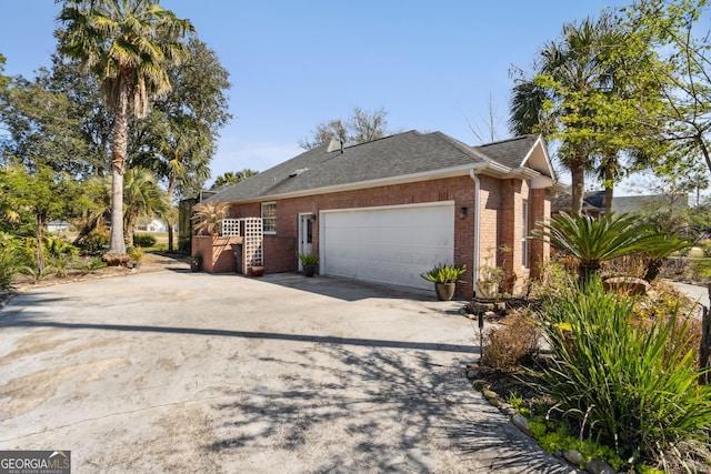 view of property exterior with a garage, concrete driveway, brick siding, and roof with shingles