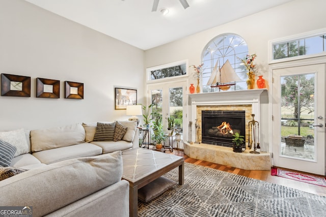 living area featuring a wealth of natural light, a glass covered fireplace, wood finished floors, and french doors