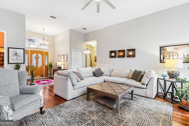 living room featuring ceiling fan with notable chandelier, wood finished floors, and visible vents