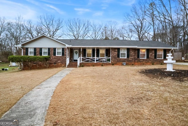 ranch-style home with crawl space, covered porch, driveway, and brick siding