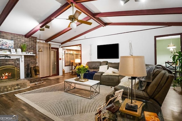 living area featuring a brick fireplace, lofted ceiling with beams, a ceiling fan, and wood finished floors