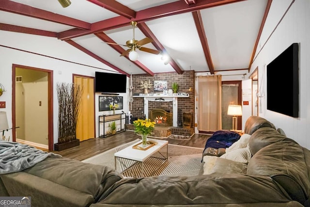 living room with lofted ceiling with beams, wood finished floors, a fireplace, and ceiling fan