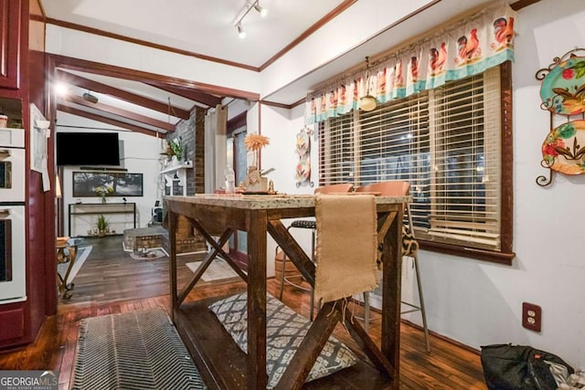 dining space featuring ornamental molding, rail lighting, lofted ceiling, and wood-type flooring