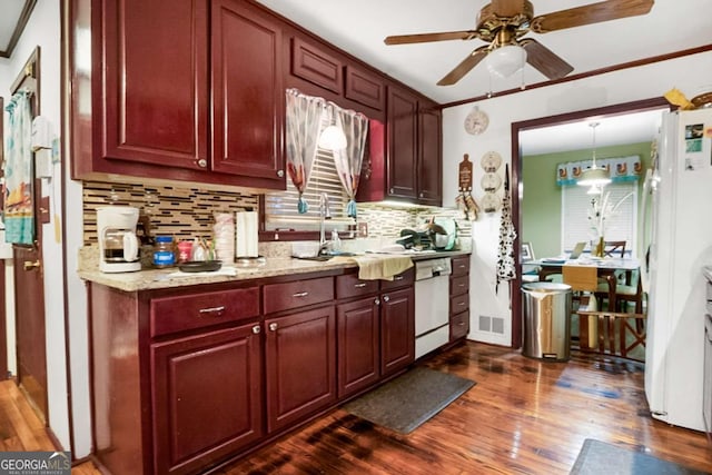 kitchen with dark wood-style flooring, white appliances, reddish brown cabinets, and a sink