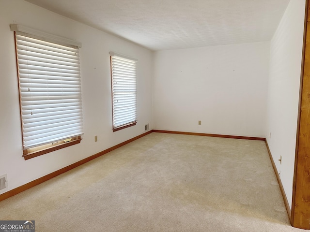 empty room with light carpet, visible vents, and baseboards