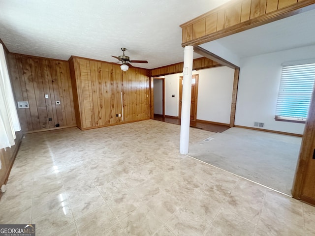 interior space with baseboards, wooden walls, visible vents, and a ceiling fan