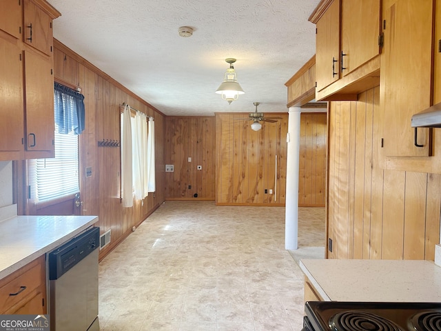 kitchen featuring light countertops, visible vents, stainless steel dishwasher, wooden walls, and a textured ceiling