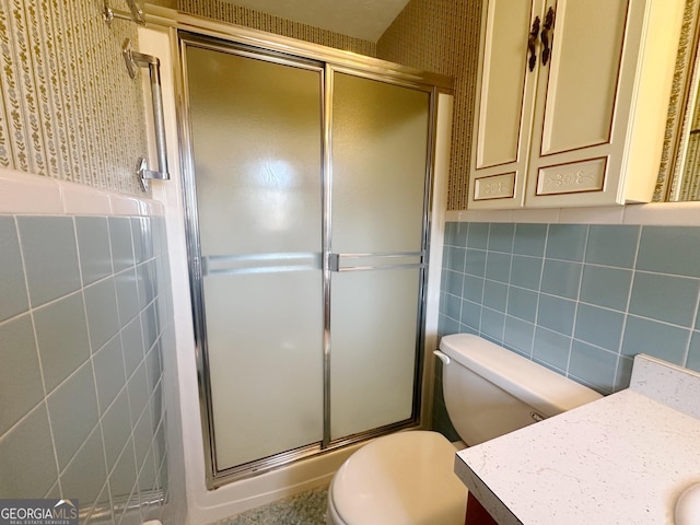 bathroom with toilet, tile walls, a shower stall, and vanity