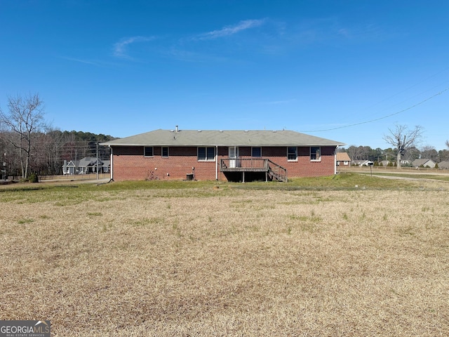 back of house with brick siding, a lawn, and a deck