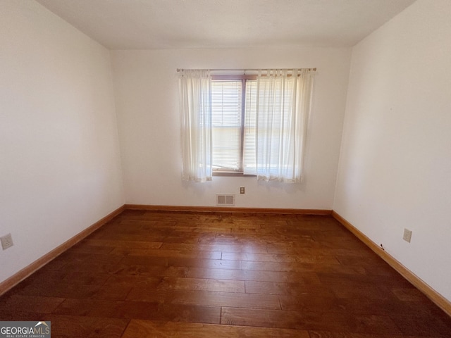 spare room with hardwood / wood-style flooring, visible vents, and baseboards