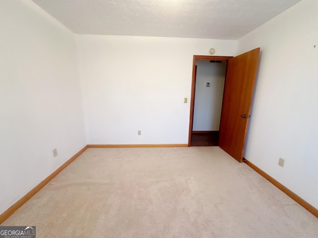 carpeted empty room with baseboards and a textured ceiling