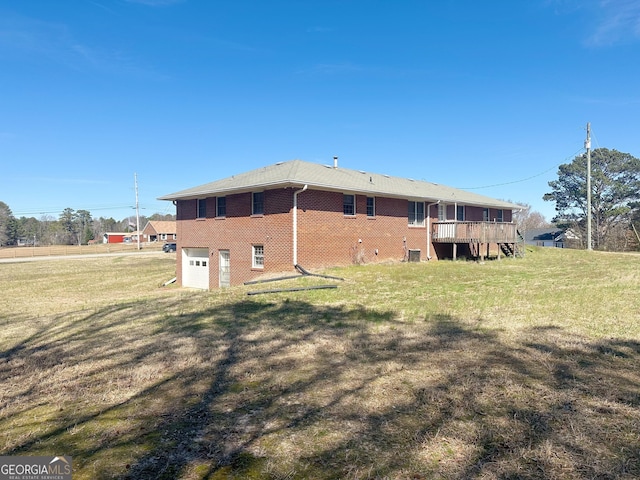 rear view of property with a garage, brick siding, a lawn, and a wooden deck