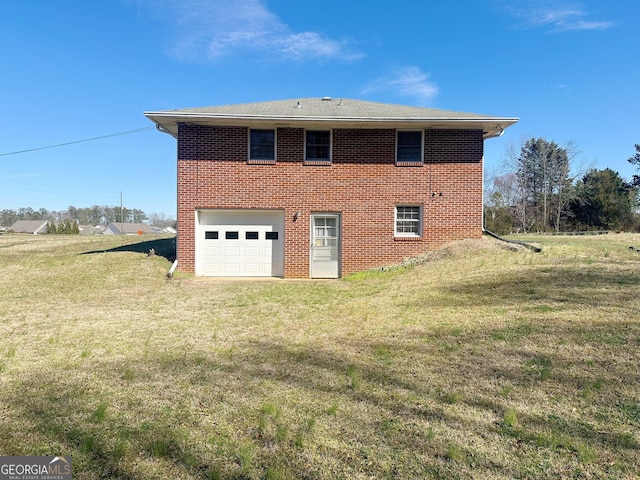 rear view of property featuring a yard, brick siding, driveway, and an attached garage