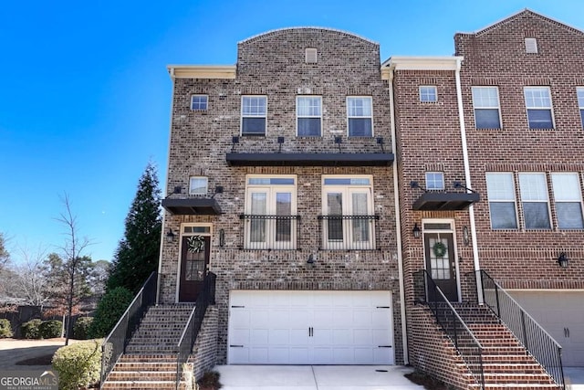 townhome / multi-family property featuring stairs, concrete driveway, brick siding, and an attached garage